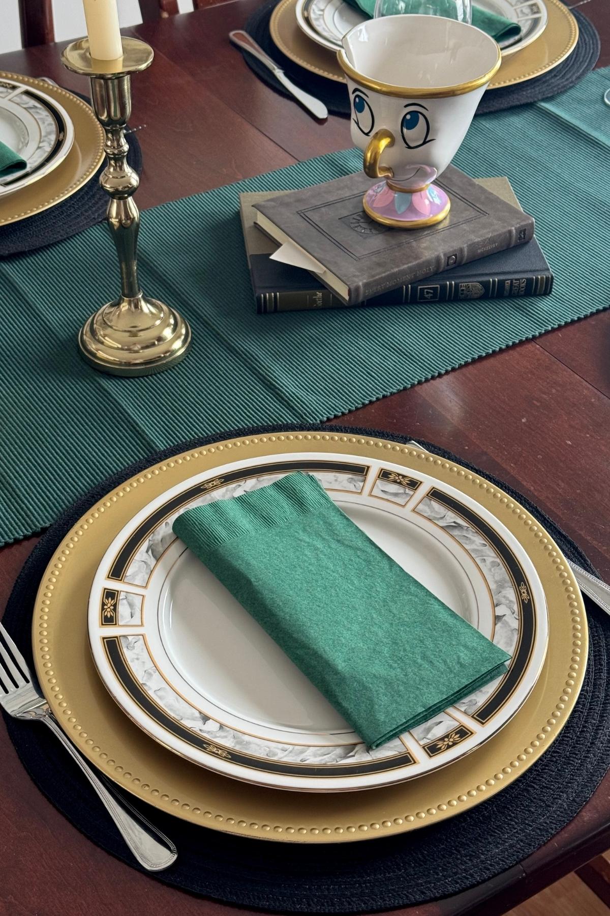 Beast's Library place setting: black placemat, gold charger, white gold and black trimmed plate, green napkin