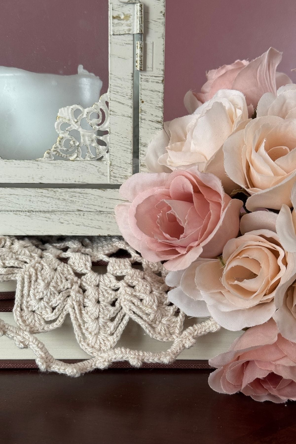 Delicate blush and ivory rose boquet on a doily covered stack of books