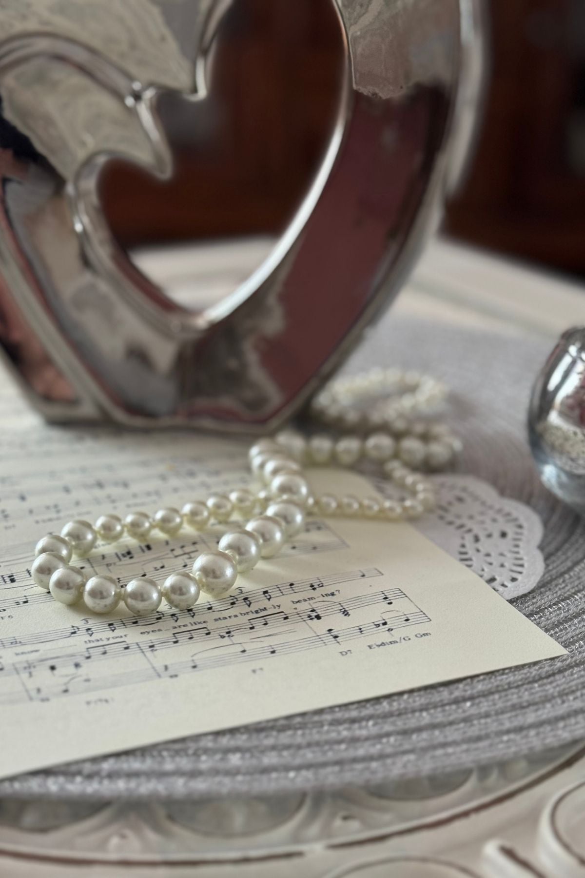 Moonlight Serenade centerpiece with sheet music, pearls, silver heart on a round silver placemat
