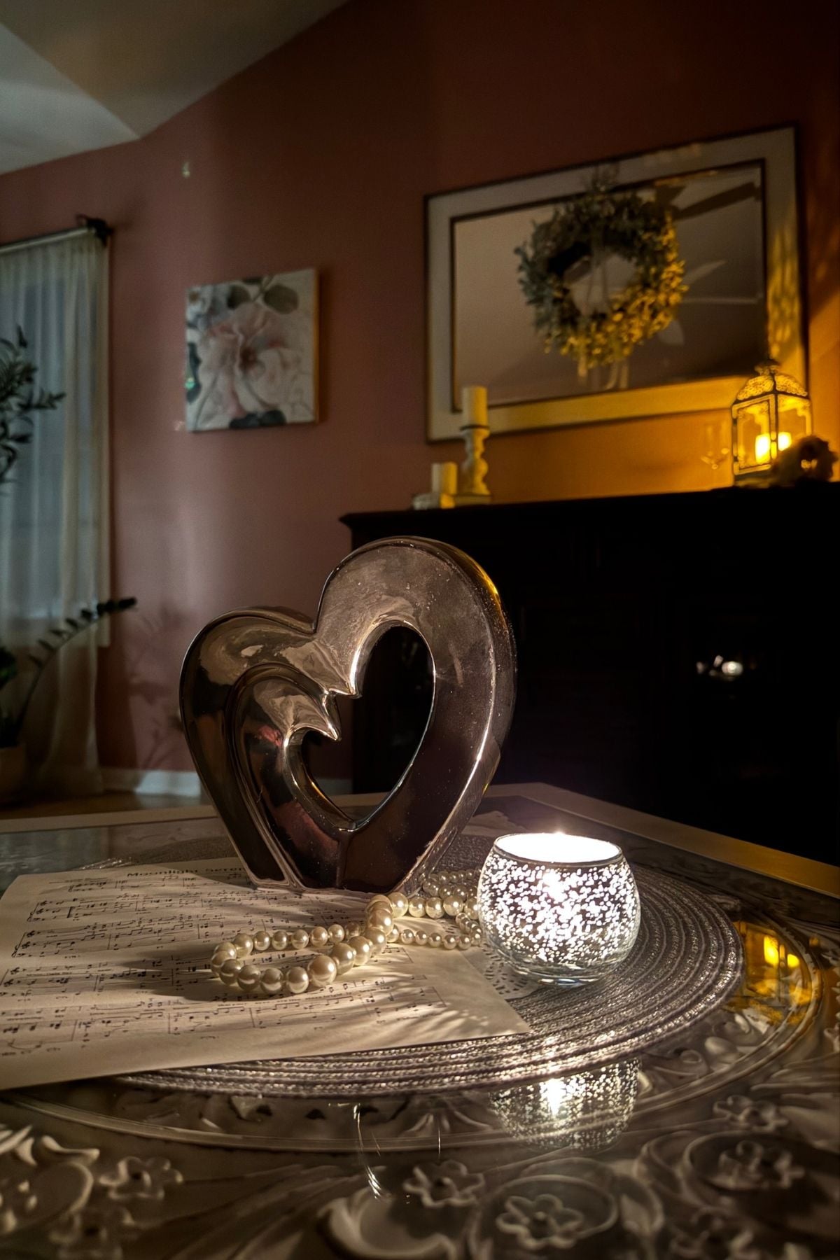 Moonlight serenade coffee table centerpiece with a heart sculpture, silver candle holder, pearls, sheet music.