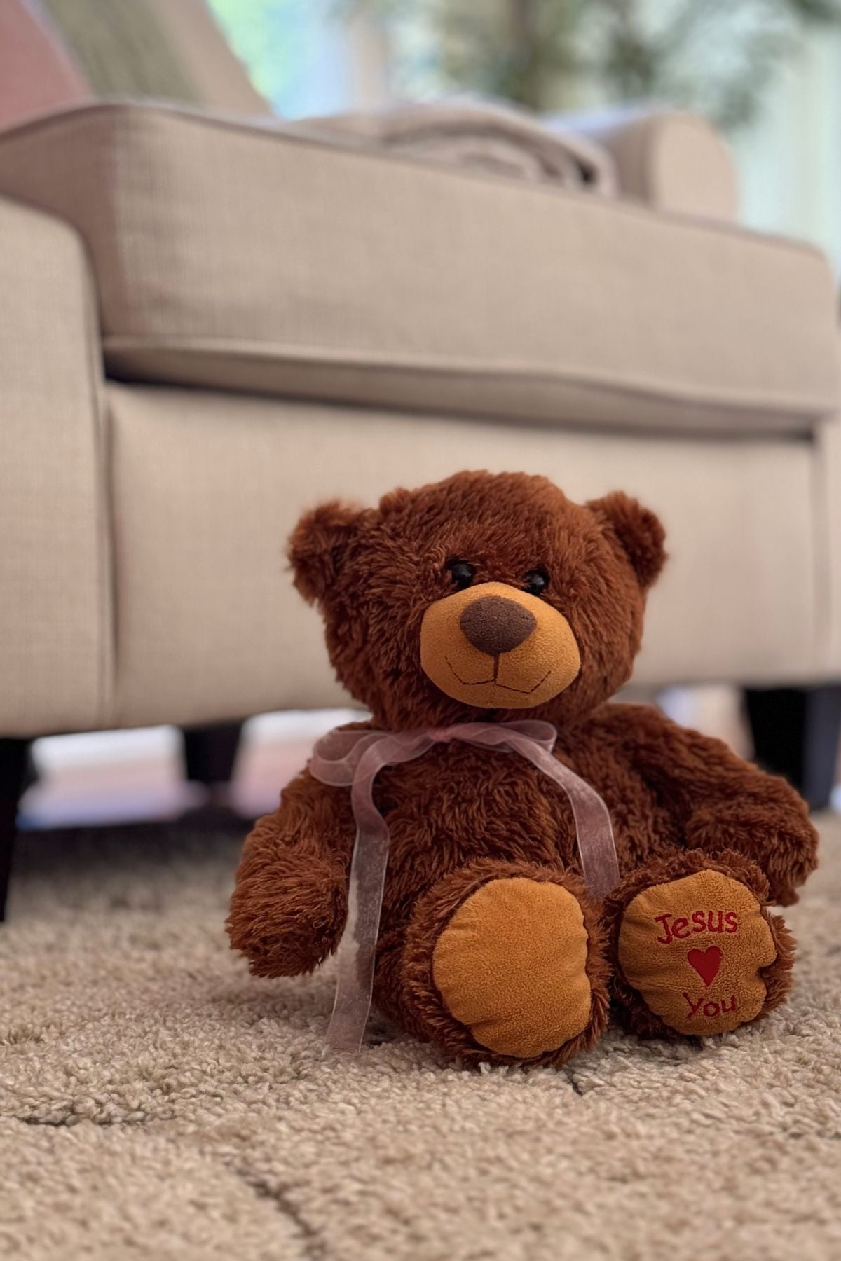 A teddy bear wearing a pink organza ribbon in a romantic summer living room.