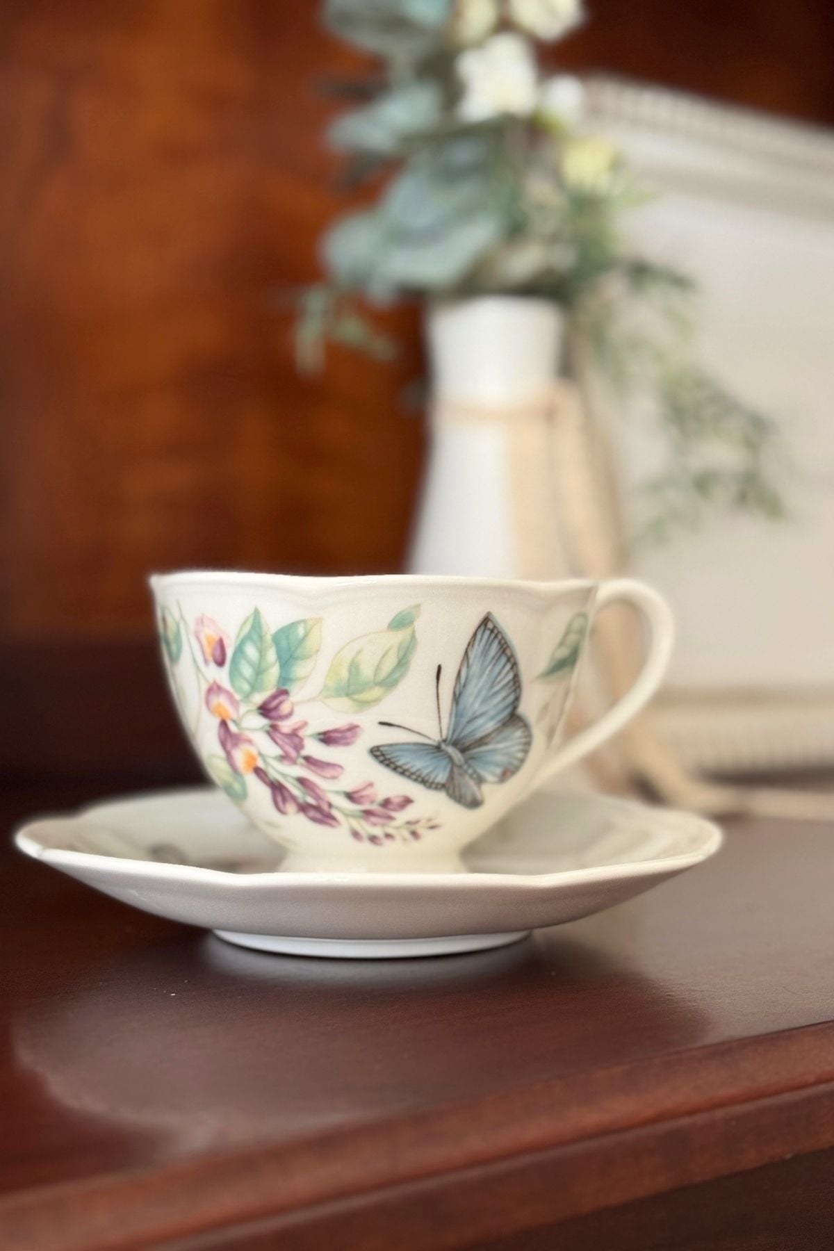 A butterfly tea cup as part of a spring decor in a china cabinet.