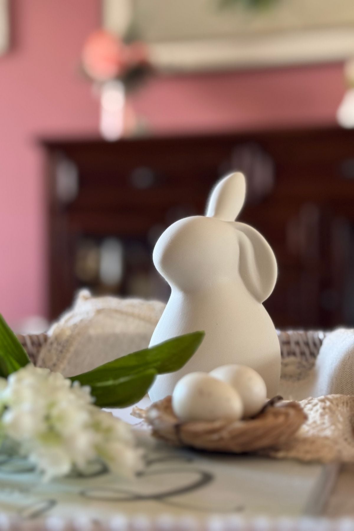 Bunny figurine beside a small nest with eggs in spring decor