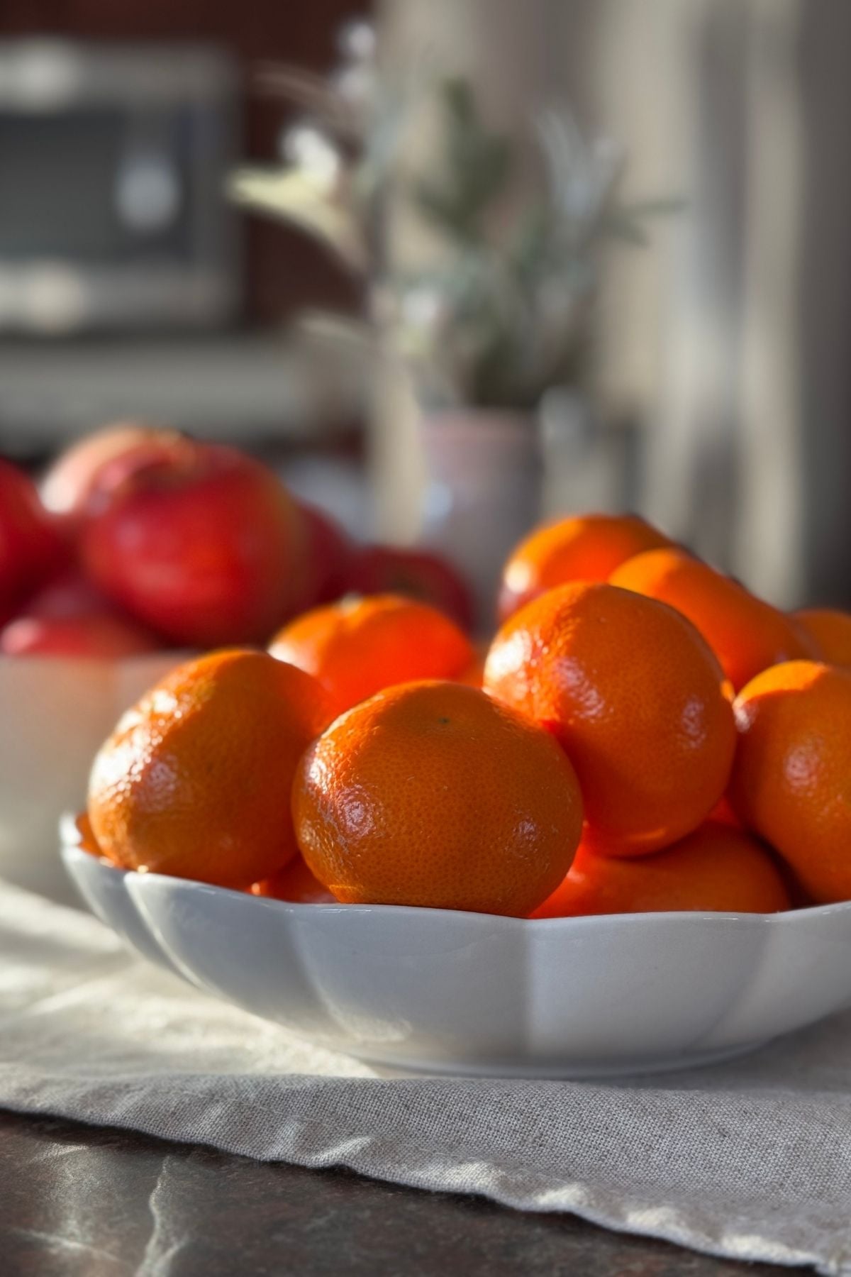 Sunlight filtering through the kitchen window and touching the oranges in a serving bowl.