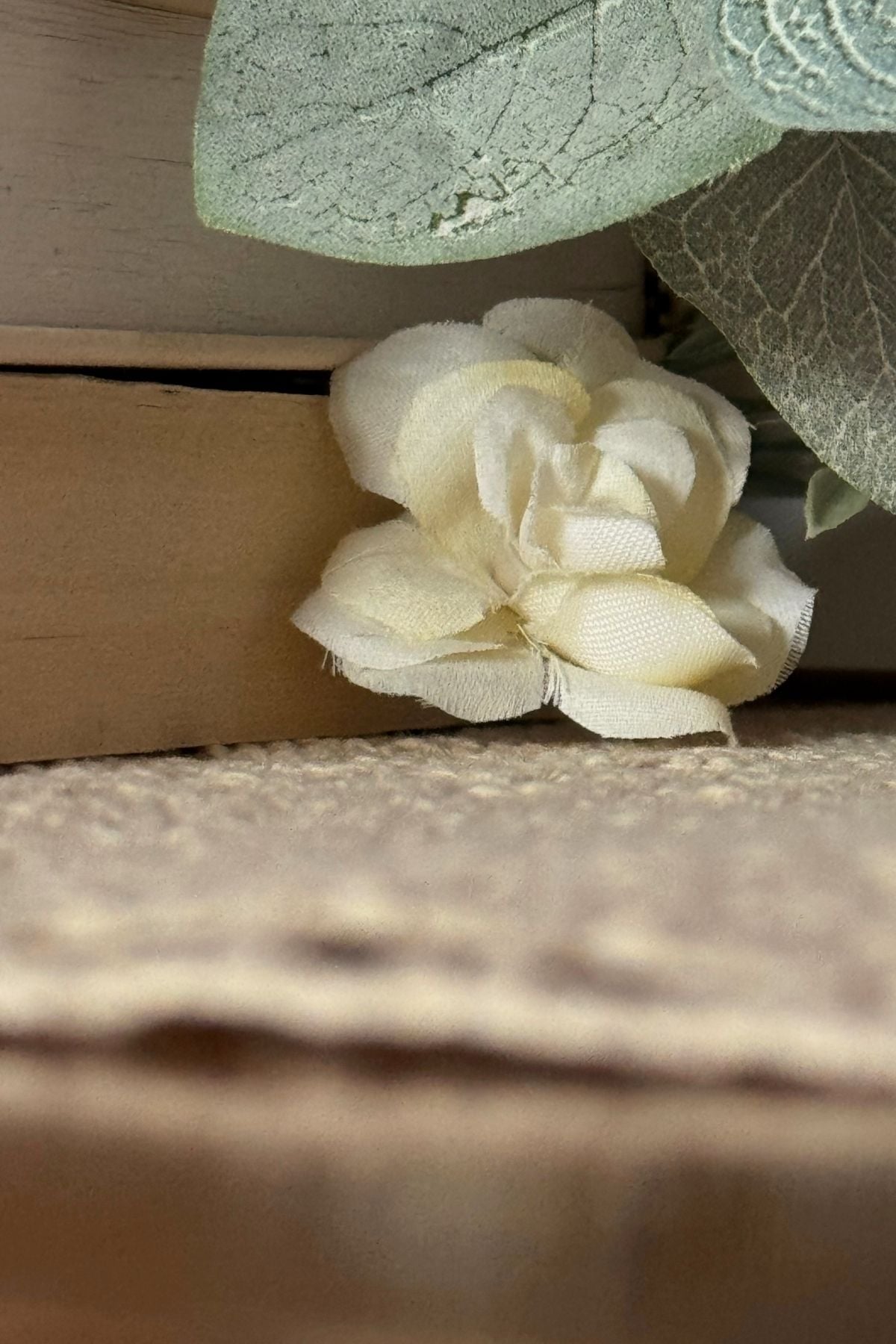 Cream floral detail tucked beneath stacked books and greenery