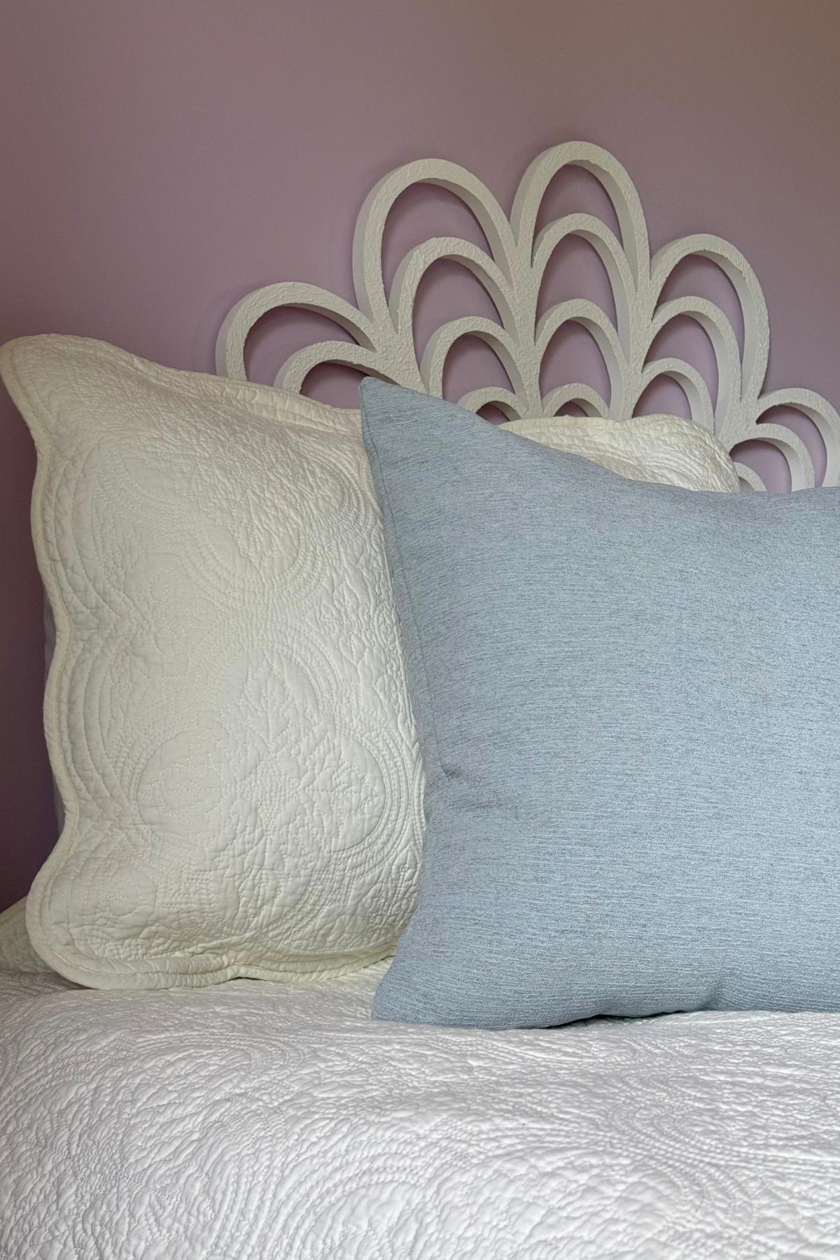Ivory quilt and misty blue throw pillows in a coastal bedroom