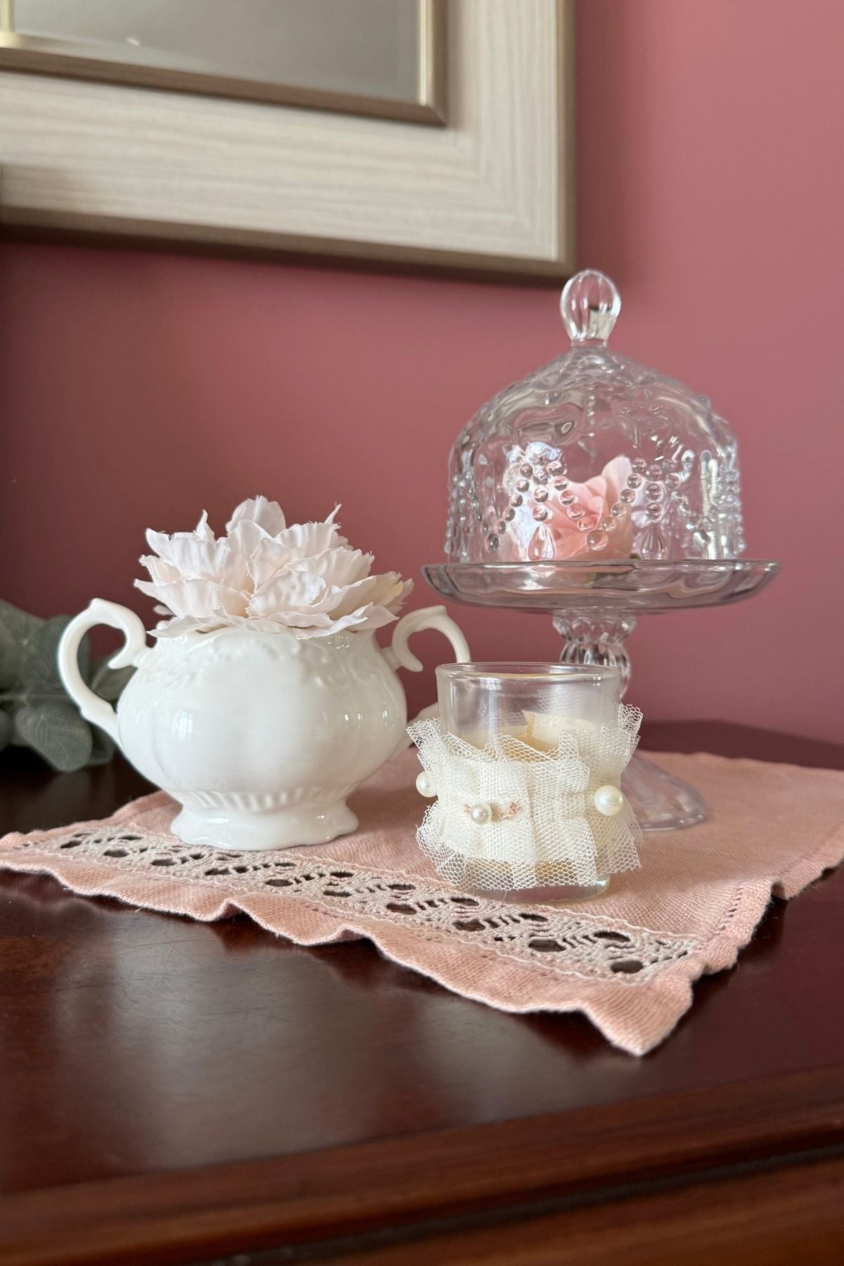 cottage decor sugar bowl Cottage-style decor with a sugar bowl, candle, and glass cloche on a dark wood sideboard.