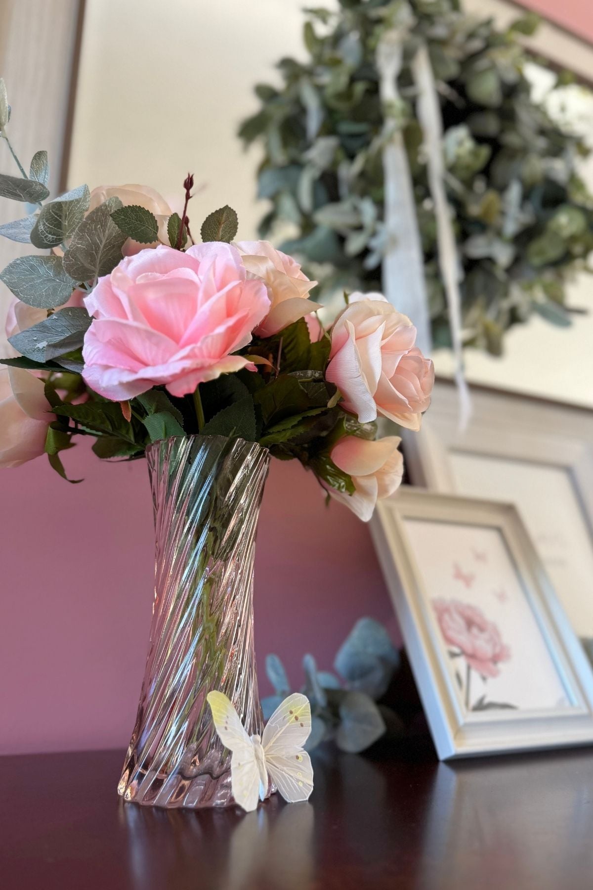 cottage decor with roses and butterflies Pink roses in a pink vase, a butterfly resting by the vase in a cottage style home.