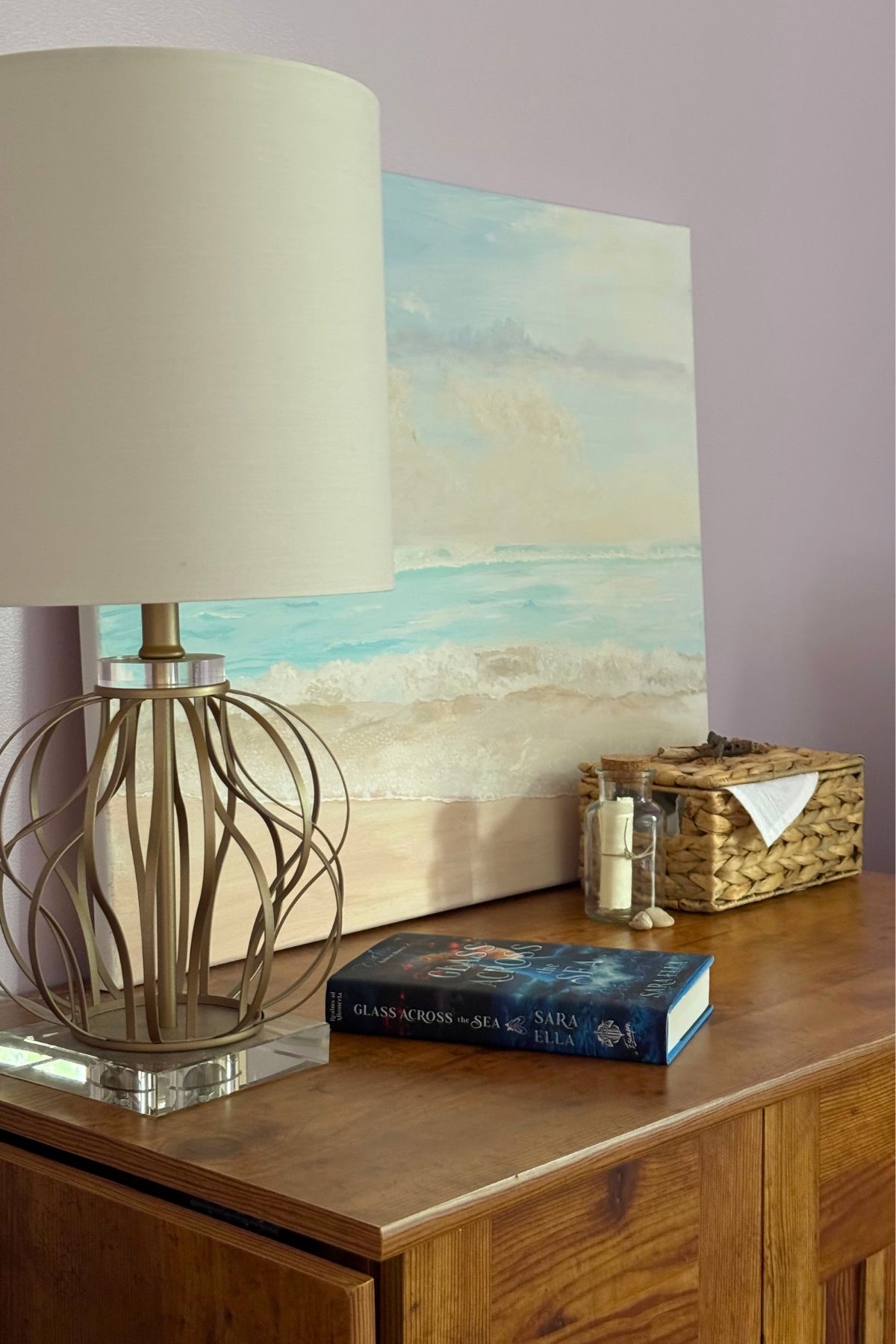 Coastal bedroom decorations: beach painting, book, message in a bottle, seagrass basket