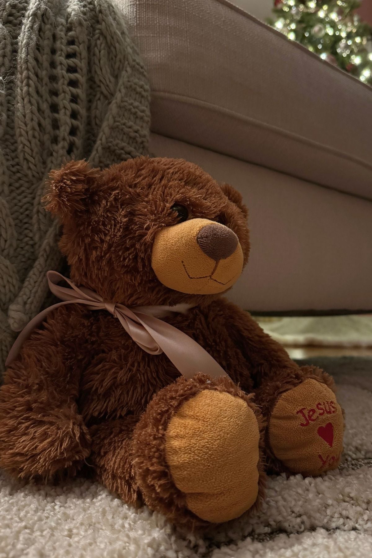 Christmas bear with a blush satin ribbon Teddy bear wearing a blush satin Christmas ribbon beside the reading chair