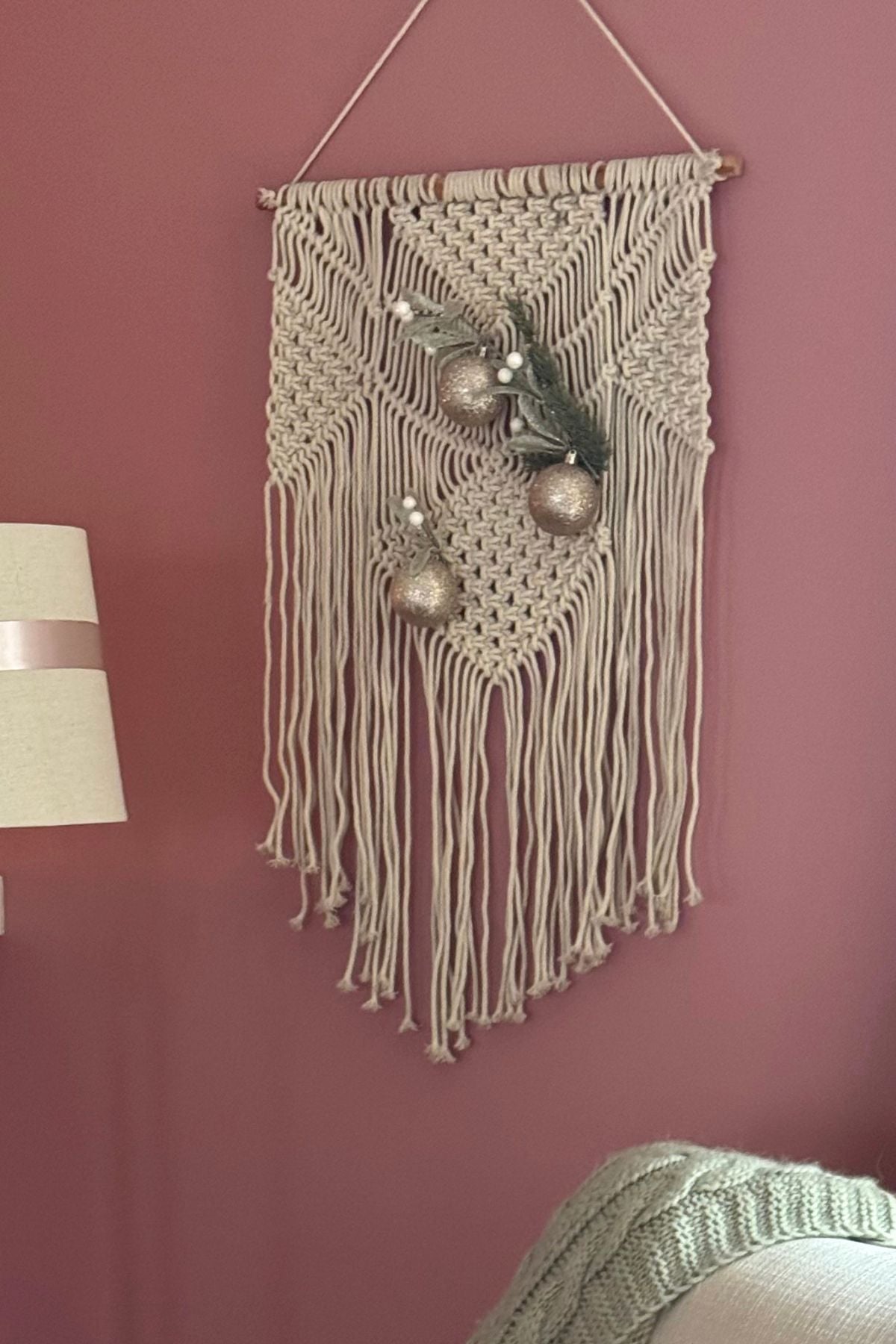 Christmas macrame Macramé wall hanging decorated with evergreen sprigs, frosted twigs, and champagne ornaments
