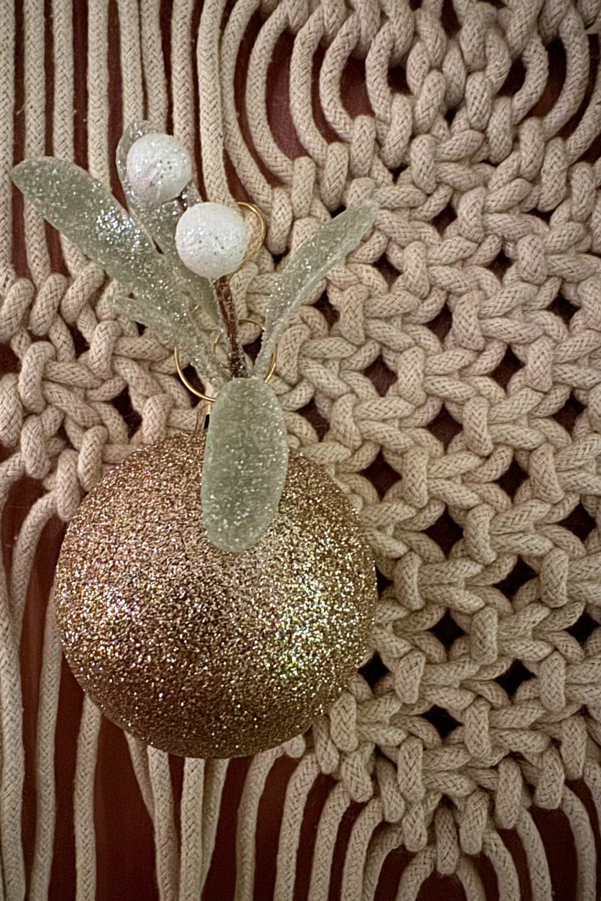 Christmas ornaments on macrame (1) Christmas styling a macarame: A champagne gold Christmas ornament attached to a macrame with a hook.