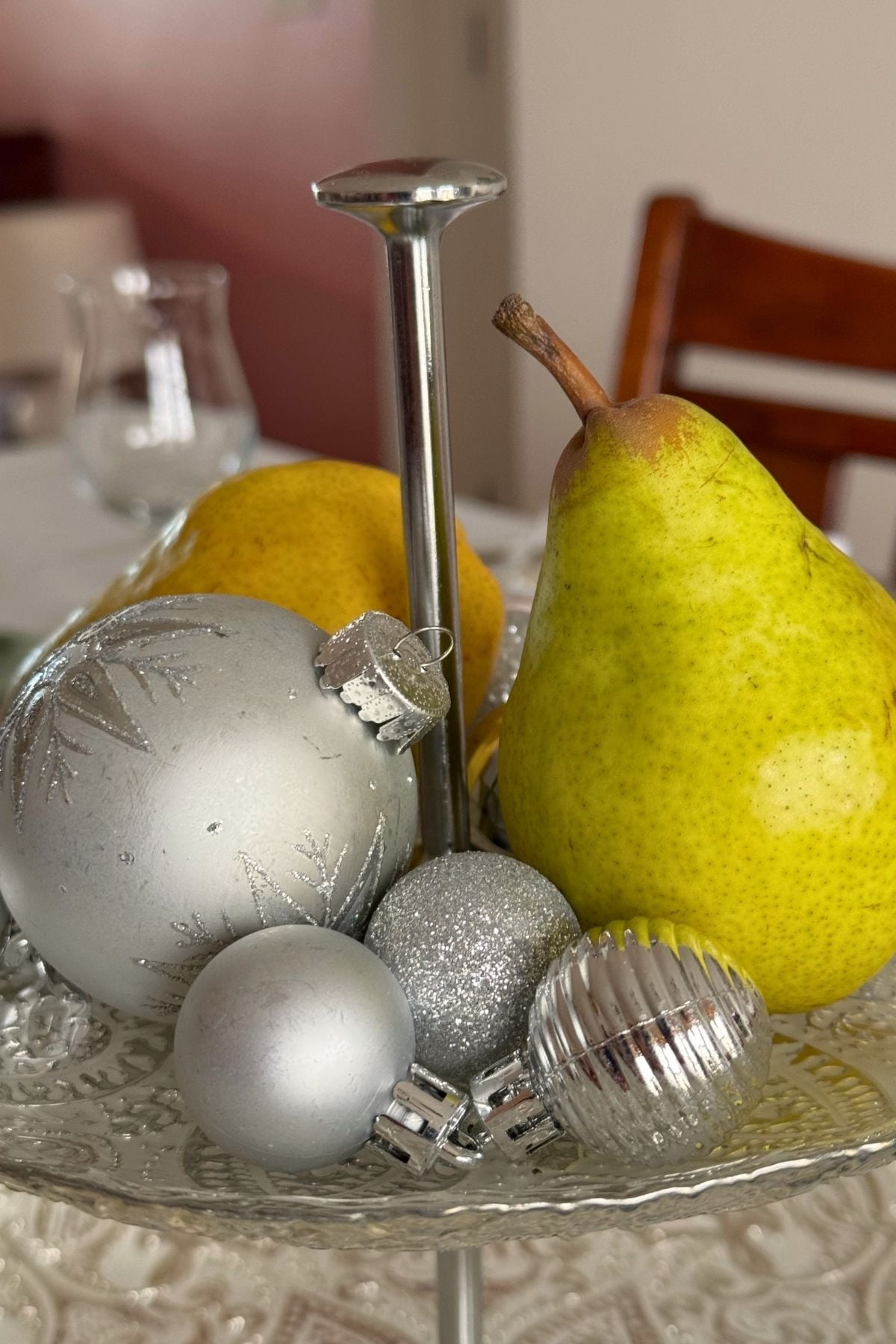decorating holiday table with pears and silver Pears and silver ornaments on a tiered stand.