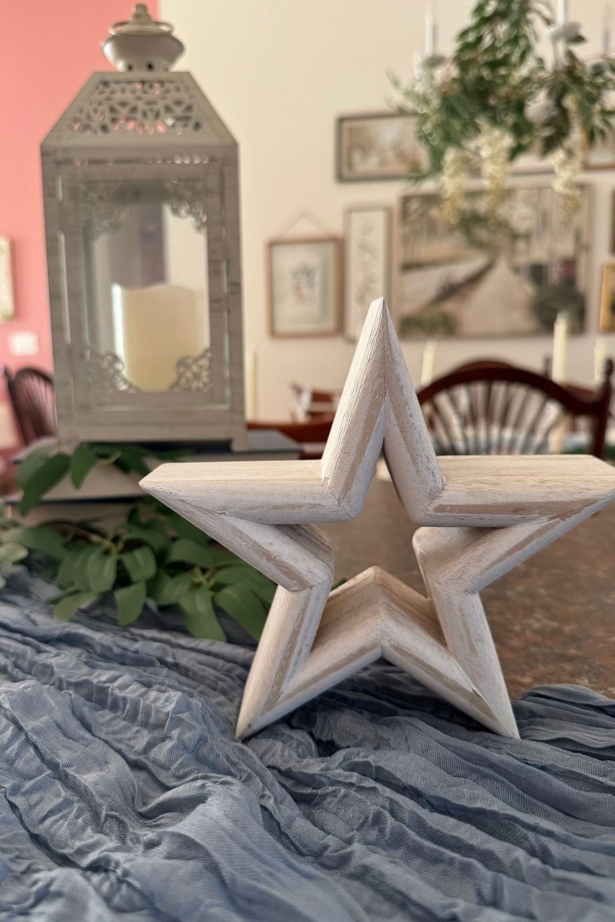 buffet table decorated with a lantern and star A dusty blue cheesecloth, white-washed wooden star, and a decorative lantern on the buffet table.