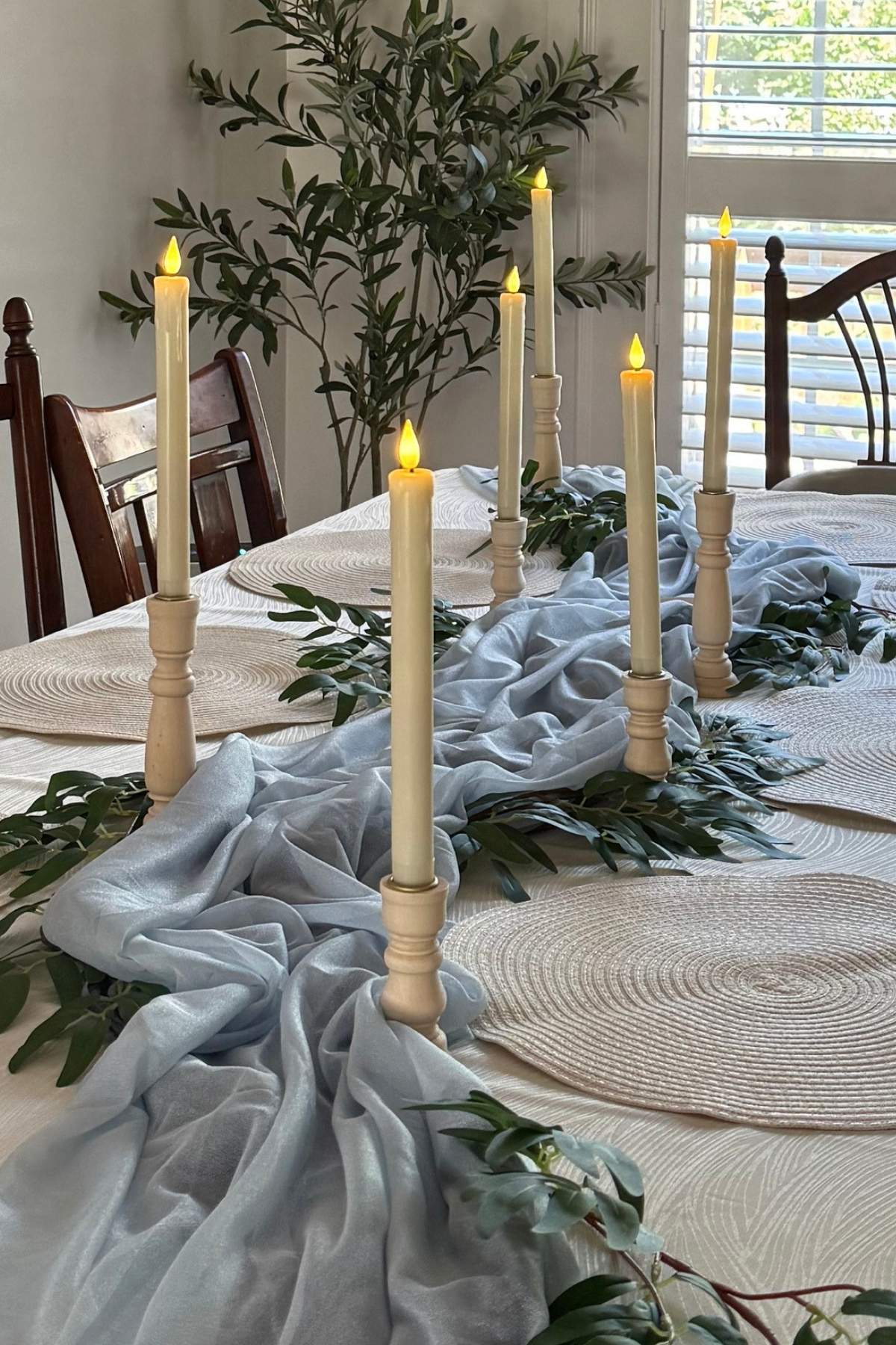 creating-blue-river-table-runner Blue chiffon table runner arranged diagonally across the table to create a winding river with greenery and ivory candle holders along the banks.