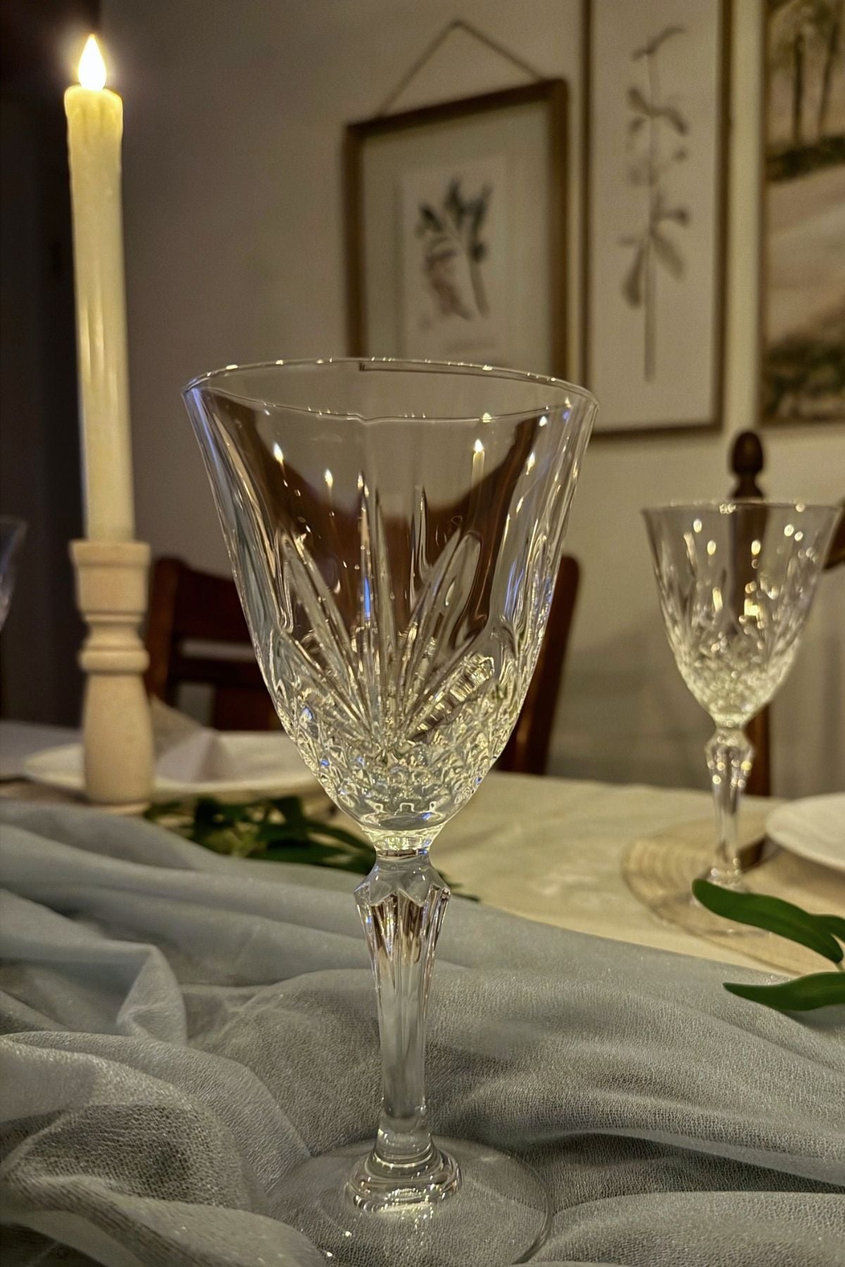 crystal wine glass Crystal wine glasses catching candlelight beside blue chiffon table runner