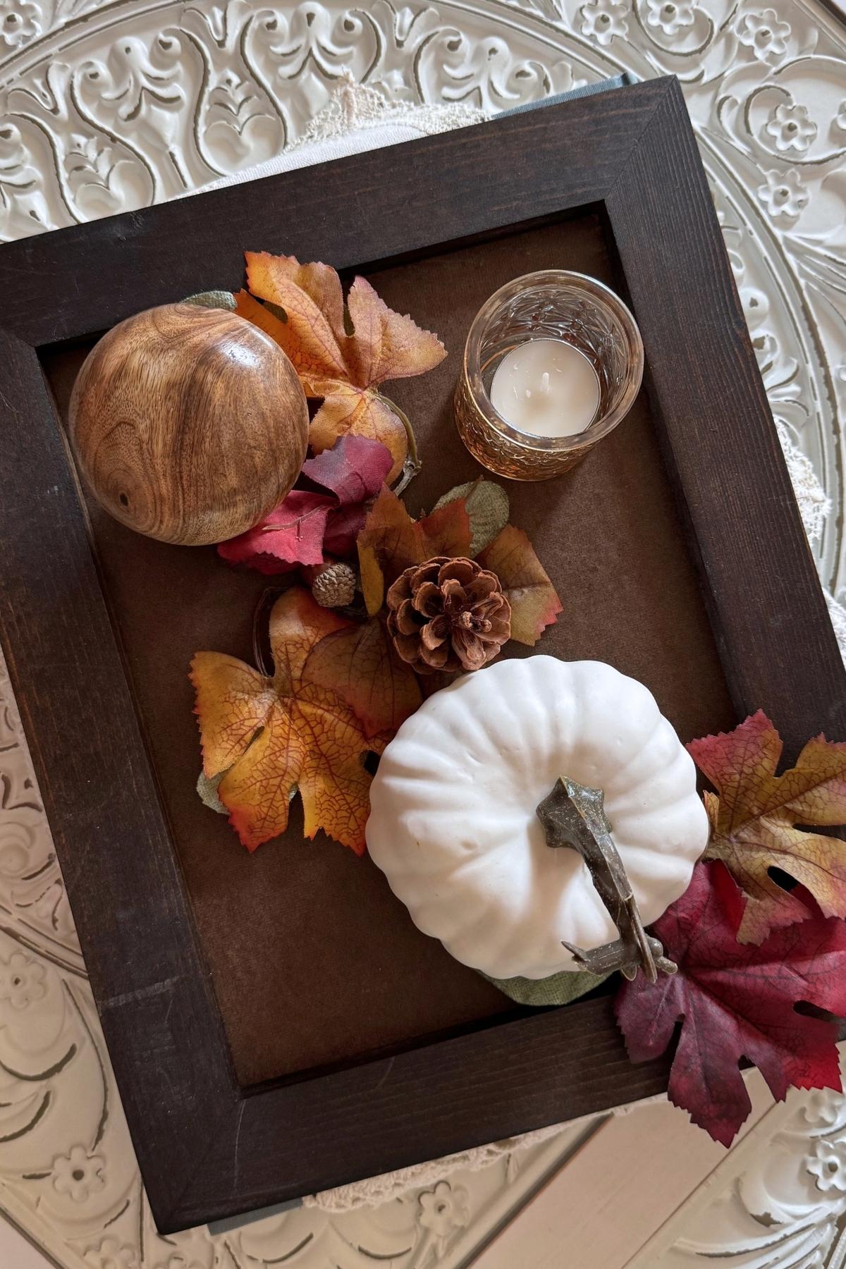 autumn tray for coffee table A dark tray with autumn decorations such as a wooden mushroom, an amber-gold candle holder, and a cream pumpkin