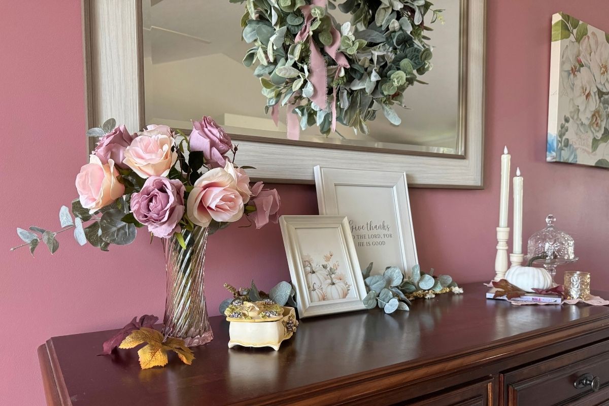 when traditional autumn colors are not yours Autumn sideboard in the living room featuring faded roses, cream frames with art, candles, and a music box